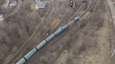 Aerial view of Train slowing riding next to industrial area Stock Footage 219745048