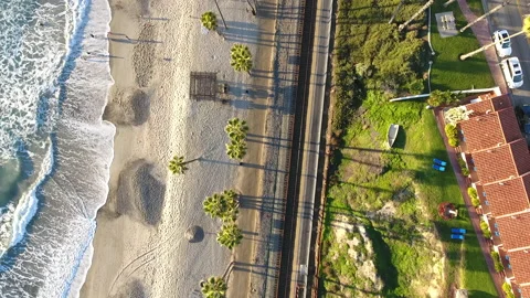Aerial view of train tracks and palm trees near waves rolling onto the shore Stock Footage 157169383