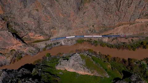 Aerial view of train winding through rugged, earthy valley (Dogu Ekspresi/Turkey Vídeo Stock 333587973