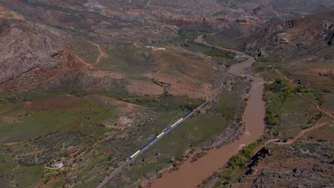 Aerial view of train winding through rugged, earthy valley (Dogu Ekspresi/Turkey Stock Footage 333588473