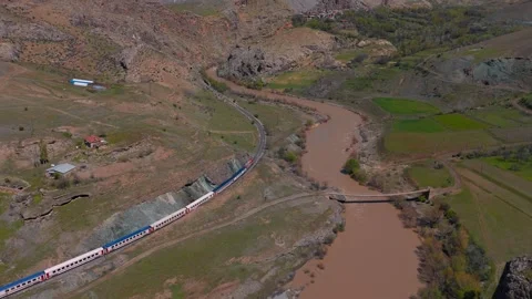 Aerial view of train winding through rugged, earthy valley (Dogu Ekspresi/Turkey Stock Footage 333589221