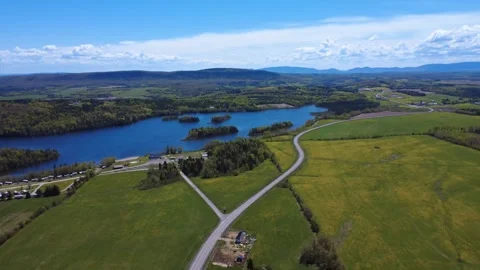 Aerial view of a tranquil lake surrounded by forests and rolling countryside Stock Footage 341443995