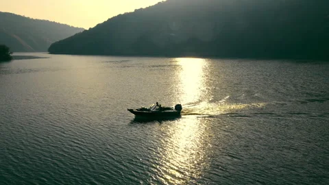 Aerial view Tranquil River Sunset with Boat, A boat glides on a river shimmering Stock Footage 267892362