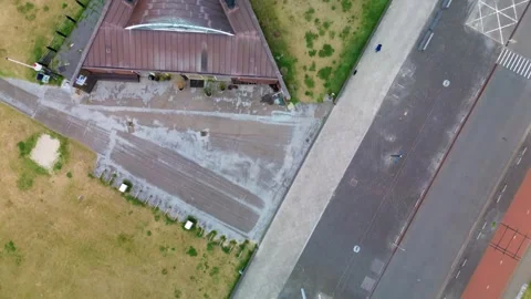 Aerial view of a triangular building near a beach, surrounded by grass Stock Footage 313754171