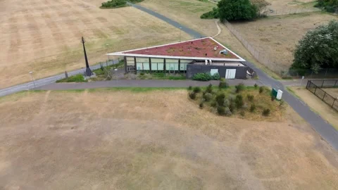 Aerial view of a triangular building near a beach, surrounded by grass Stock Footage 313754176