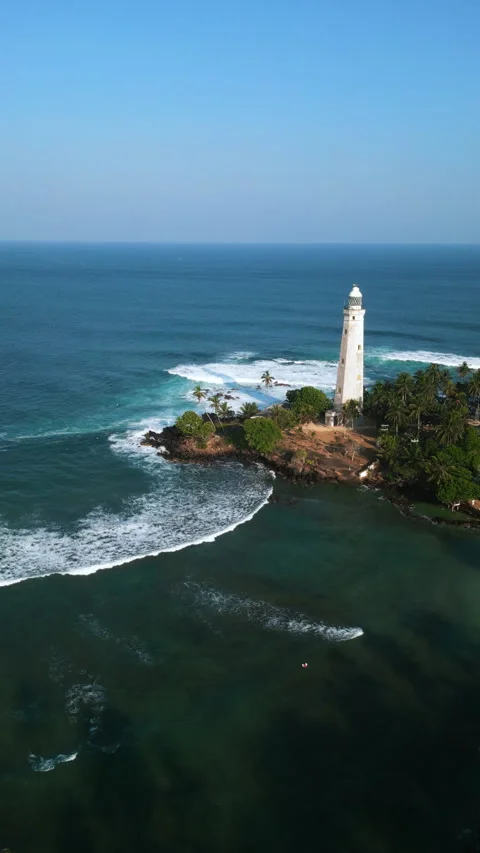 Aerial view tropical lighthouse surrounded by lush palm trees with waves Stock Footage 269046965
