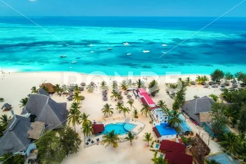 Aerial view of tropical sandy beach with palms and umbrellas, sea Stock Photos