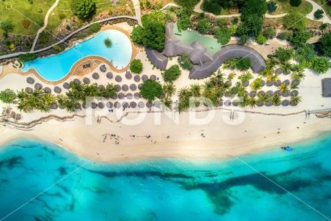 Aerial view of tropical sandy beach with palms and umbrellas, sea Stock Photos