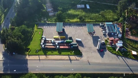 Aerial view of a truck stop with multiple trucks parked alongside a road and Stock Footage 313318009