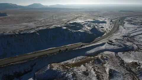Aerial view of trucks and suvs moving along the highway in the desert in winter Video stock 80243797