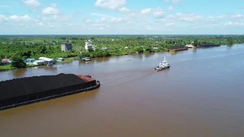 Aerial view of a tugboat pulling a barge filled with coal in the waters of .. Stock Footage 313063265