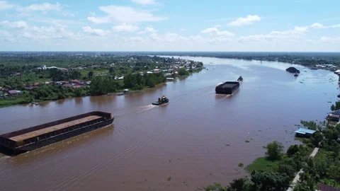 Aerial view of a tugboat pulling a barge filled with coal across the Rumpiang Br Stock Footage 313096104