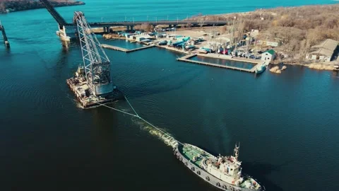 Aerial view tugboat pulling floating crane to shipyard in river Stock Footage 172470974