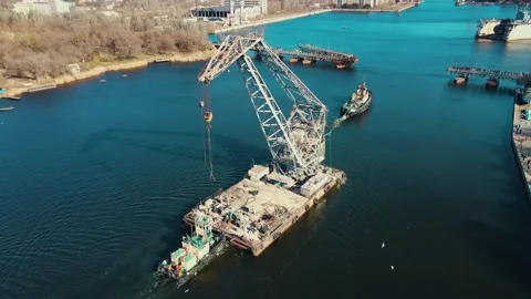 Aerial view tugboat pulling floating crane by river in city of shipbuilders Stock Footage 174661832
