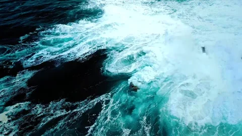 Aerial view of turbulent ocean waves crashing against jagged dark rocks Stock Footage 343696493