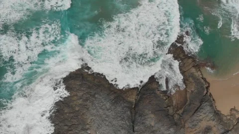 Aerial View of Turquoise Ocean Waves Crashing on Dark Rocky Coastline Stock Footage 295749272
