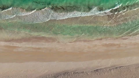 Aerial view of turquoise ocean waves washing onto a sandy beach. Stock-Footage 323429438