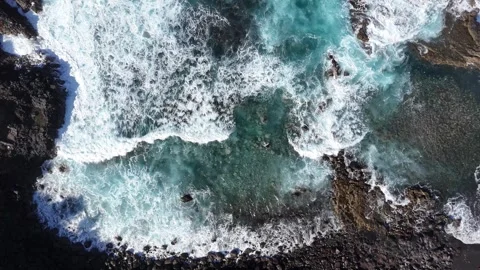 Aerial view of turquoise ocean waves crashing against rocky shoreline. Dynamic Видео 335877023