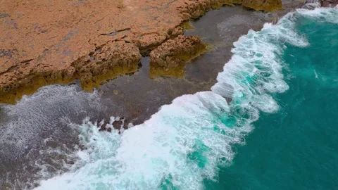 Aerial View of Turquoise Ocean Waves Crashing on Rocky Coast Stock Footage 339159474