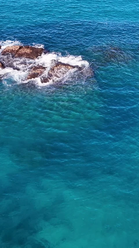 Aerial View of Turquoise Ocean Waves Crashing Against Coastal Rocks Stock Footage 341842627