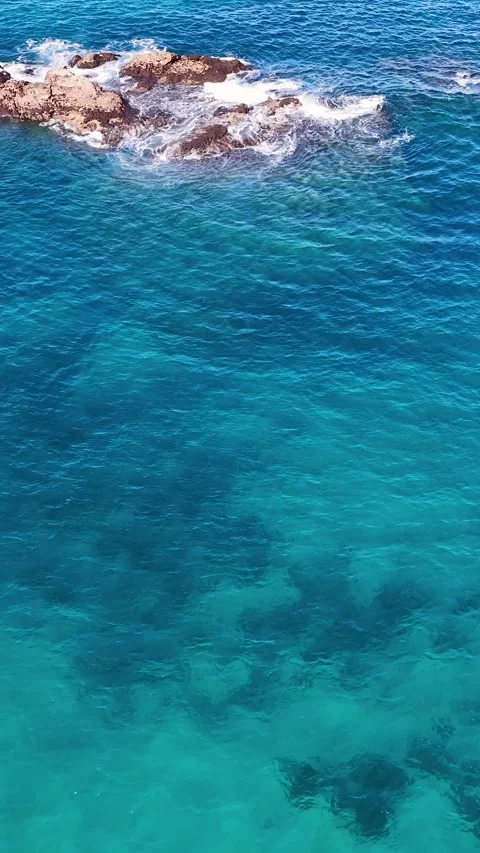 Aerial View of Turquoise Ocean Waves Crashing Against Rocks Stock Footage 341852476