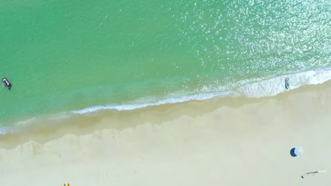 Aerial view of turquoise ocean waves gently rolling onto a pristine sandy beach Stock Footage 342093867