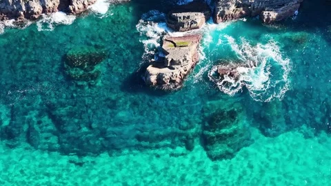 Aerial View of Turquoise Ocean Waves Crashing Against Coastal Rocks Video stock 342231197