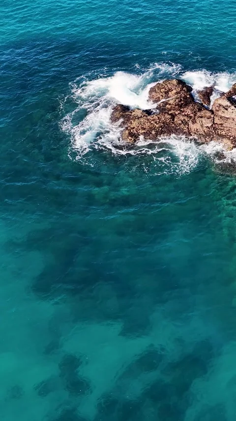 Aerial View of Turquoise Ocean Waves Crashing Against Coastal Rocks Video stock 342231284