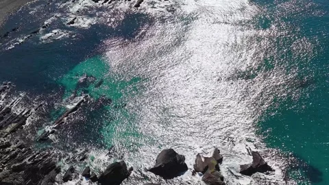 Aerial View of Turquoise Ocean Waves Crashing Against Coastal Rocks Video stock 342231315