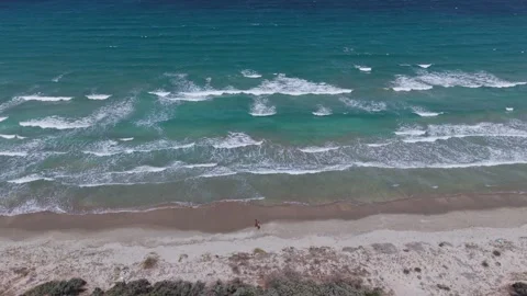 Aerial view of turquoise ocean waves rolling toward a sandy coastline bordered Video stock 344140996