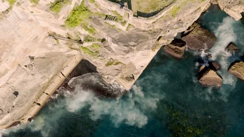 Aerial View of Turquoise Ocean Waves Crashing Against Rugged Rocky Coastline Stock Footage 346120945