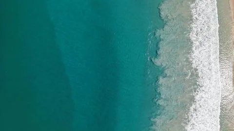 Aerial view of turquoise ocean waves meeting sandy beach shoreline Photos