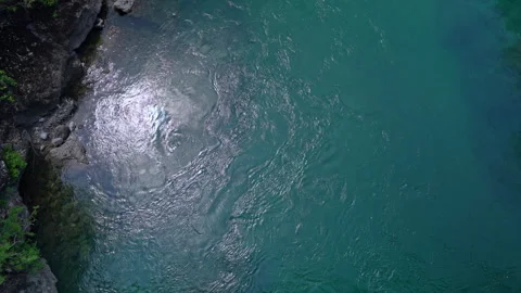 Aerial view of turquoise river water rippling beside rocky bank Видео 343899587