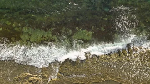 Aerial View: Turquoise waves gently kiss a golden beach, surrounded by lush Stock-Footage 296027943