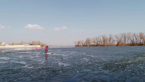 Aerial view of two athletes on the SUP. Winter. Ice. Slowmotion. Stock Footage 73296902