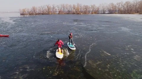 Aerial view of two athletes on the SUP. Winter. Ice. Slowmotion. Stock Footage 73298165