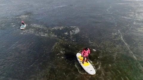 Aerial view of two athletes on the SUP. Winter. Ice. Slowmotion. Stock Footage 73299524