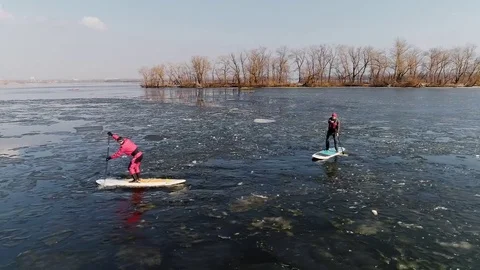 Aerial view of two athletes on the SUP. Winter. Ice. Slowmotion. Stock Footage 73299766