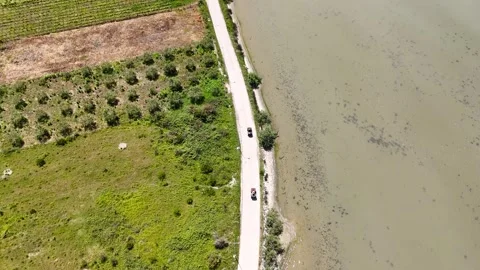 Aerial view of two ATVs riding along a winding rural road near a pond Stock-Footage 336450332