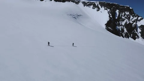 Aerial view of two backcountry skier ascending a mountain with rope Stock Footage