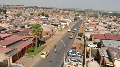 Aerial view of two bicycle spinners performing stunts on a busy road in Soweto Stock Footage 239454554