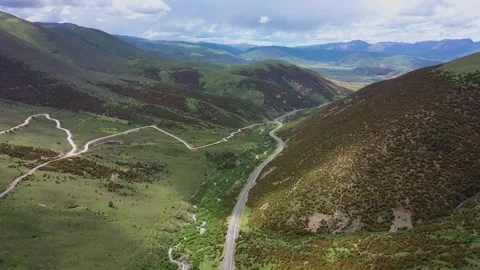 Aerial view of two converging mountain roads in green valley basin of Daocheng Stock Footage 336698455