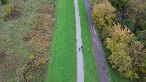 Aerial view of two cyclists riding along a scenic path surrounded by vibrant Stock-Footage 330053087