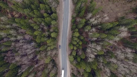 Aerial view of two-lane forest road with cars trucks moving Stock Footage 84500218
