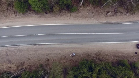 Aerial view of two-lane forest road with cars trucks moving Stock Footage 84500704