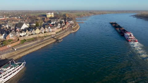 Aerial view of two large cargo ships navigating a wide river, with grassy Vídeos de archivo 334136978