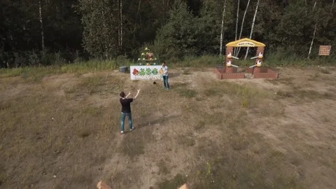 Aerial view two men playing giant slingshot game knocking down plushies outside Stock Footage 72289229