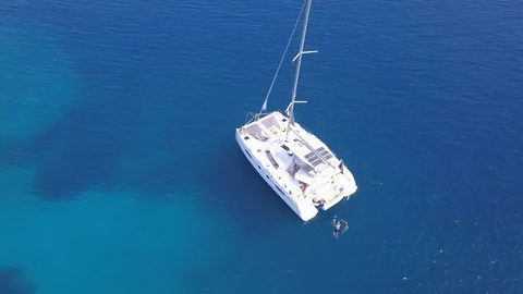 Aerial view two people bathe in the blue sea near a sailboat Stock Footage 120292875