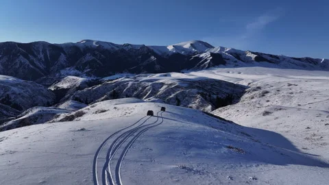 Aerial view of two off-road vehicles driving on a snowy mountain ridge Stock Footage 321734983