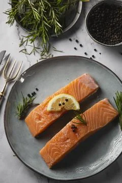 Aerial view of two salmon fillets served on a plate with lemon and rosemary o Stock Photos